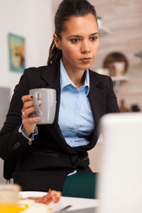 Mid adult woman holding drink at table