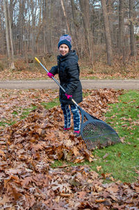Young girl rakes leaves in her yard on a cool fall day
