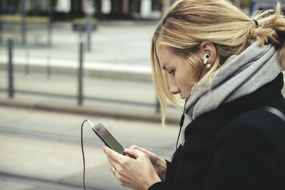 Side view of businesswoman using smart phone at tram station