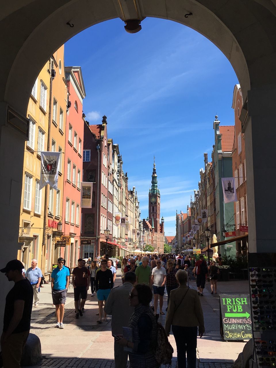 architecture, building exterior, built structure, city, large group of people, person, men, street, sky, city life, walking, building, lifestyles, residential building, residential structure, sunlight, window, arch, day