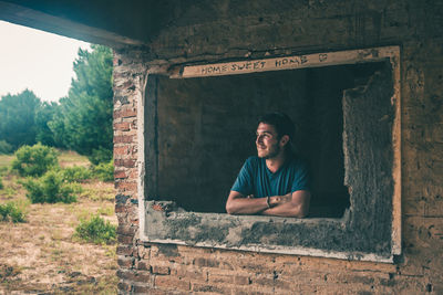 Man looking through window of incomplete house