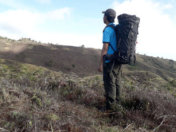 Rear view of man standing on land against sky