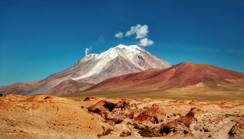 Scenic view of volcanic mountain against blue sky