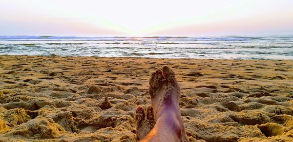 Low section of person on beach against sky