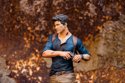 Young man looking away while standing on rock