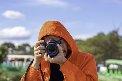 Close-up of mature man photographing with camera against sky