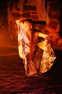 Woman wearing costume while dancing in darkroom