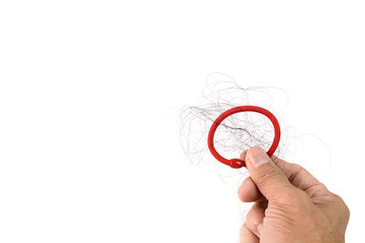 Close-up of hand holding ring over white background