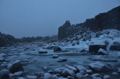 Rocks on snow covered land against clear sky
