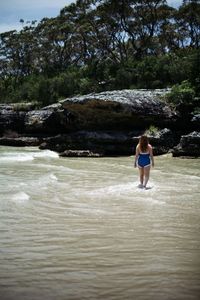 Rear view of young woman standing at beach