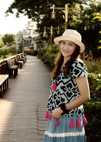 Portrait of smiling young woman standing against trees