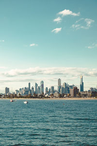 City at waterfront against cloudy sky