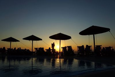 Silhouette people by sea against clear sky during sunset