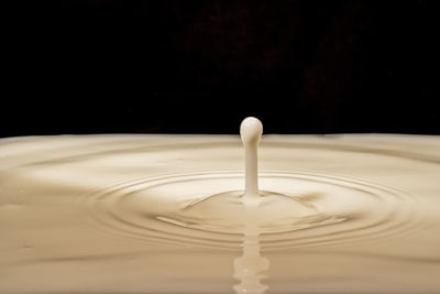 Close-up of drop splashing on water against black background