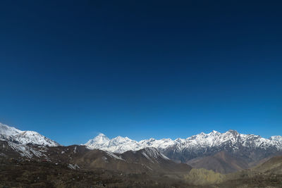 Scenic view of snowcapped mountains against clear blue sky