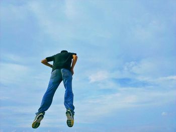 Low angle view of woman standing against blue sky