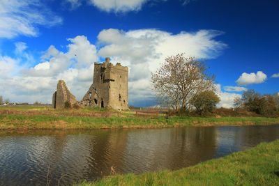 Old ruins of sragh castle by canal against cloudy sky