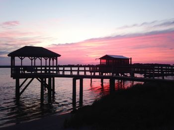 Gazebo in sea against sky during sunset