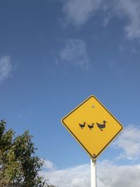 Ducks crossing yellow sign against a blue sky vertical