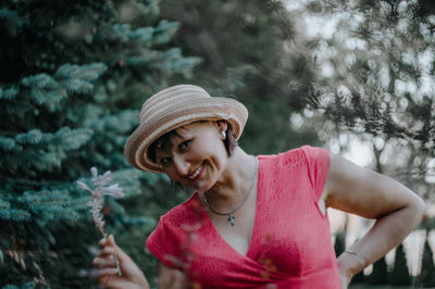 Portrait of happy mature woman holding flowers while standing at park