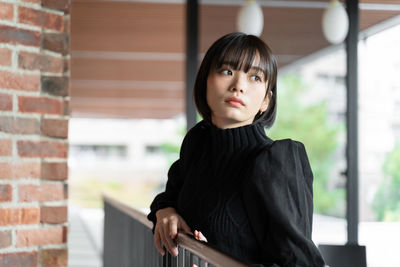 Young woman standing against brick wall