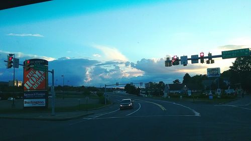 View of vehicles on road against cloudy sky