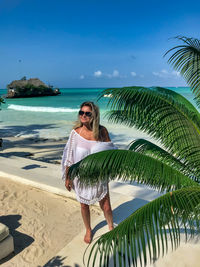 Young woman standing at beach against sky