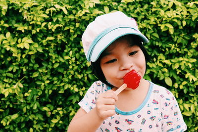 Cute girl eating candy against plants