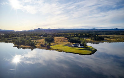 Amazing scenery of river coastline with solitary country house and woodland against highland at horizon in fair weather