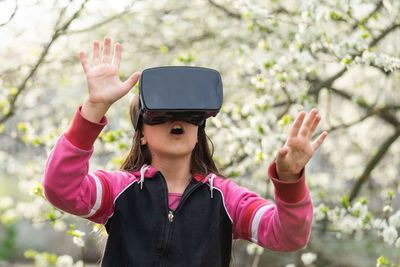 Happy amazed little girl wearing virtual reality goggles watching movies or playing video games. 