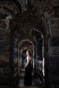 Portrait of woman standing against stone wall