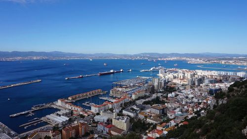 High angle view of town by sea against blue sky