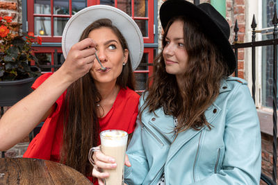 Two cheerful pretty young women talking and laughing in outdoor cafe, having fun together