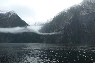 Scenic view of lake by snowcapped mountains against sky