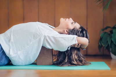 Side view of young woman doing yoga on exercise mat