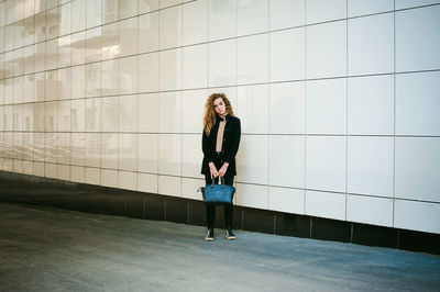 Portrait of woman standing against wall