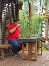 Side view of young man sitting on table