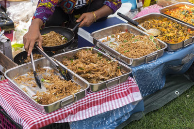 Midsection of woman serving noodles at market stall