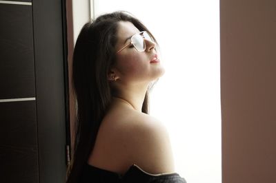 Close-up of young woman standing against wall