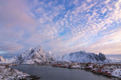 Scenic view of sea by snowcapped mountains against sky during sunset