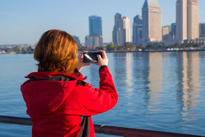 Young woman uses a smart phone to video a beautiful view in the dontown san diego.