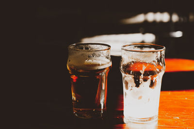 Close-up of beer glass on table against black background