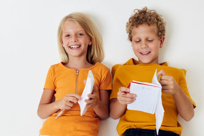 Smiling kids holding notebook against white background