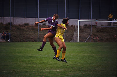 Full length of friends playing soccer on field