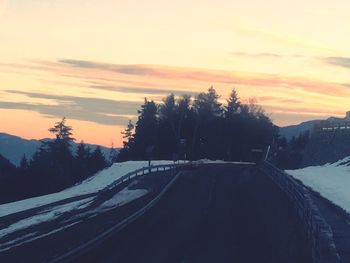 Road amidst trees against sky during winter