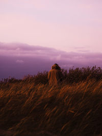 Rear view of couple standing on grassy field during dusk