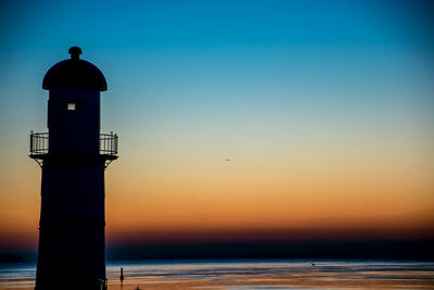 Silhouette lighthouse against sky during sunset