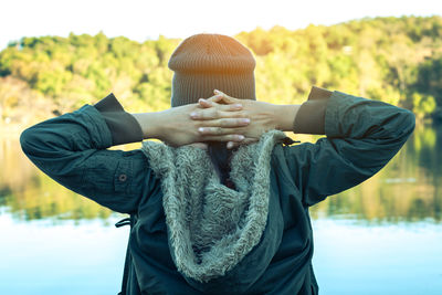 Rear view of person wearing hat standing on field during winter
