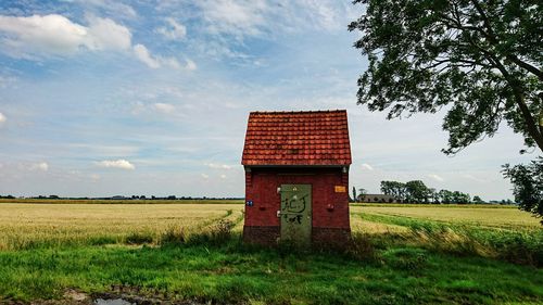 Shed on grassy field against sky