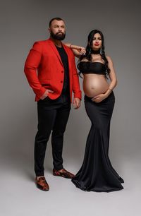 Portrait of young couple standing against gray background